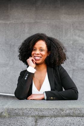 Creative Highlights Symbolbilder An African American woman displays a friendly smile, casually posing with a hand on her chin outdoors, dressed in professional attire. Model Released AidaMartinez_ID18989_565220_005 Copyright: xAidaxMartinezx RECORD DATE NOT STATED