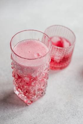 Two textured glasses featuring a refreshing cherry vodka and tonic cocktail with effervescent bubbles and ice cubes, against a soft background. Model Released AnnaBogush_ID19984_591792_001 Copyright: xAnnaxBogushx