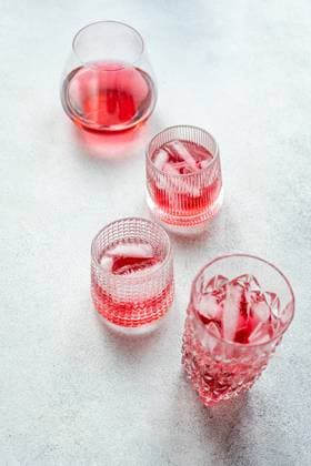 Top view of elegant glasses filled with a refreshing cherry vodka and tonic cocktail, accompanied by ice cubes, set on a textured surface. Model Released AnnaBogush_ID19984_591795_002 Copyright: xAnnaxBogushx