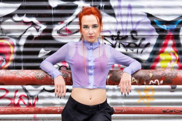 Creative Highlights Symbolbilder MR_ID19556_16504_NataliaPenado.jpg A Caucasian female poses against an edgy backdrop of colorful graffiti. Her striking red hair contrasts with her sheer lilac blouse and black slacks looking at camera Model Released GemaAlejo_ID19556_580309_012 Copyright: xGemaxAlejox