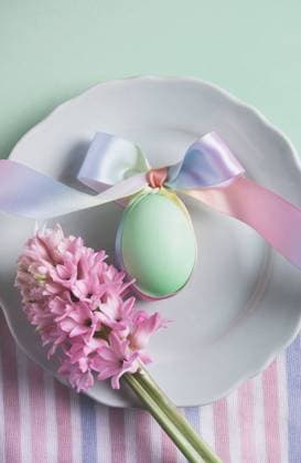 Top view soft pastel-hued Easter setting featuring a decorated egg tied with a multi-colored ribbon on a white plate, accompanied by pink hyacinth flowers. Model Released HelenaNechaeva_ID20002_592153_003 Copyright: xHelenaxNechaevax RECORD DATE NOT STATED