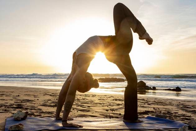 Creative Highlights Symbolbilder A yoga feamle practitioner performs a challenging pose on a sandy beach as the sun sets, creating a tranquil and inspiring setting. Model Released JuanAizpuru_ID19654_582782_040 Copyright: xJuanxAizpurux