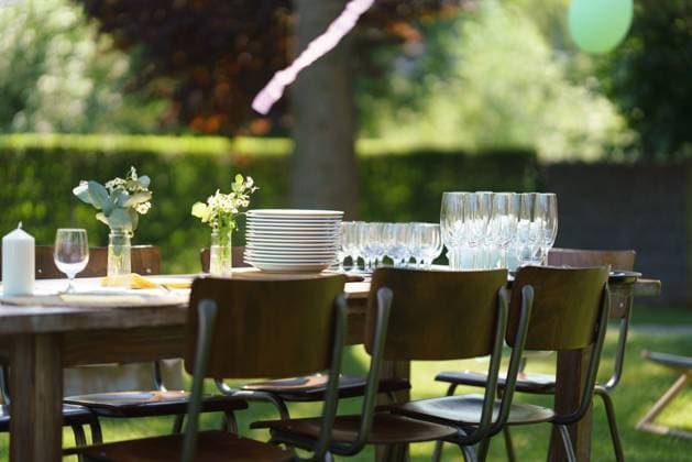 Set table at summer garden party, empty plates and glasses. Table setting with glasses, lemonade, delicate floral and paper decoration. Close up shot of set table at summer garden party, empty plates and glasses. Table setting with glasses, lemonade, delicate floral and paper decoration. model released