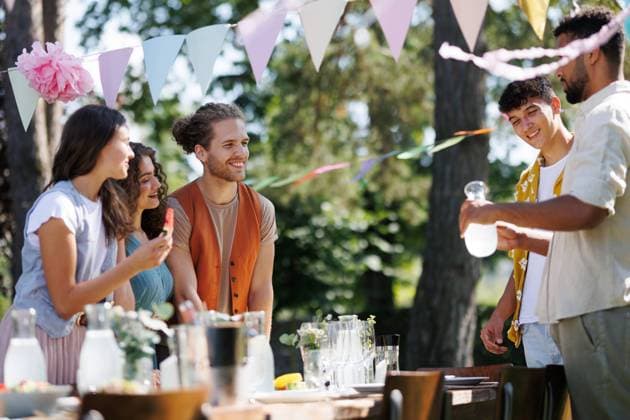 Friends and family talking and eating barbeque specialties at a summer grill garden party. Friends and family talking, having fun and eating barbeque specialties at a summer grill garden party. model released
