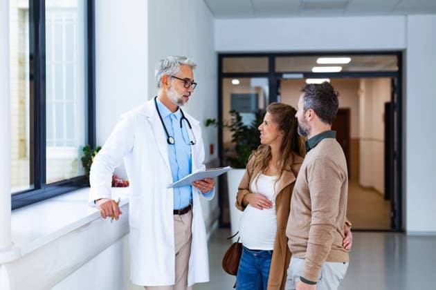 Pregnant woman and husband talking to obstetrician in hospital. Admitting woman in labor to maternity ward, planned cesarean section delivery. Pregnant woman and husband talking to obstetrician in hospital. Admitting woman in labor to maternity ward, planned cesarean section. model released