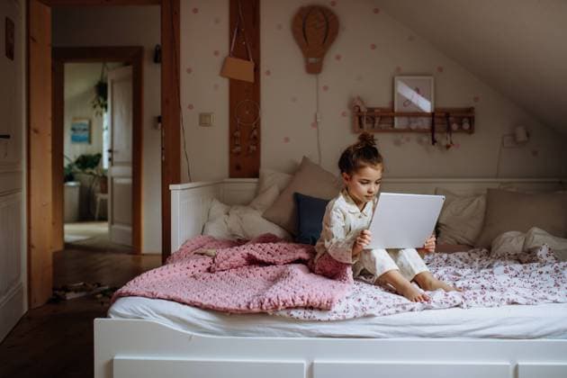 Cute girl sitting on bed watching something on tablet. Children s screen time. Cute girl sitting on bed and watching something on tablet. Children s screen time. model released