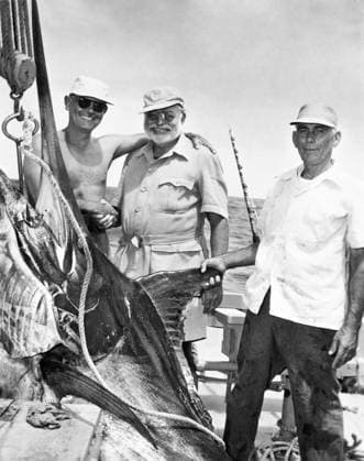 ERNEST HEMINGWAY (1899-1961). American writer, center, with Cuban sportsman Elicio Arguilles, Jr., and fishing boat captain Gregorio Fuentes in Cuba during the filming of The Old Man and the Sea, 1956.  Copyright: xGRANGERx xGRANGERx 0012655