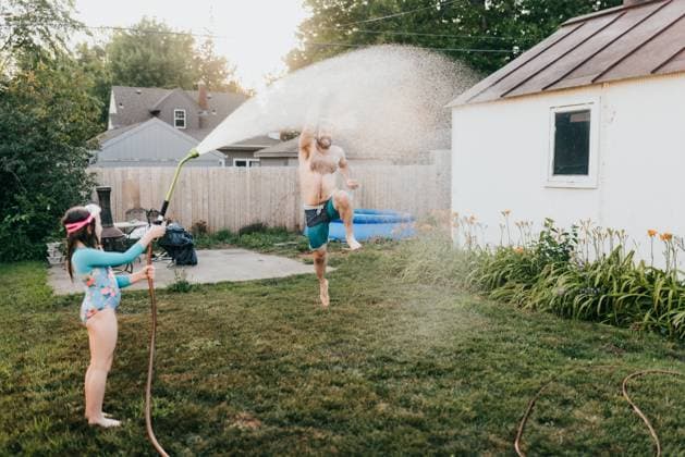 Young girl holds garden hose while dad runs through water Sioux Falls, South Dakota, United States CR_ASWE240317-1369124-01 ,model released, Symbolfoto ,property released