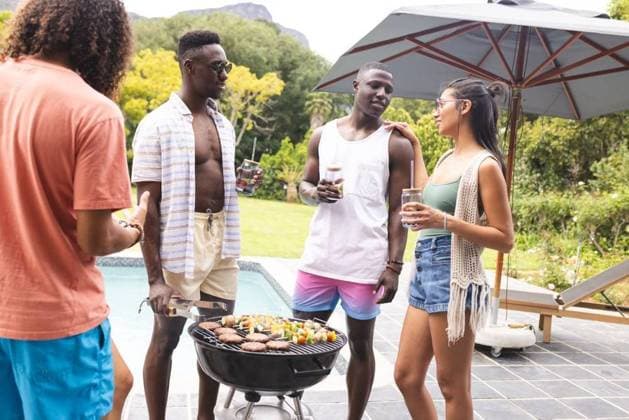 Diverse friends enjoy a barbecue outdoors, with a young African American man at the grill Diverse friends enjoy a barbecue outdoors, with a young African American man at the grill. They are chatting and holding drinks, creating a relaxed and social atmosphere., model released, , property released, Cape Town, South Africa, 15.11.2023, 4951688.jpg, people,diverse friends,barbecue,outdoors,African American,grill,chatting,drinks,relaxed,social atmosphere,friends,gathering,diverse,food,cooking,socializing,happy,happy people,joyful,outdoor activity,leisure,diversity,friendship,relaxation,summer,cookout,happiness,young,men,women,multicultural,unity,fun,picnic,conversation,connection,togetherness,celebration,lunch,dinner,meal,event,community,enter
