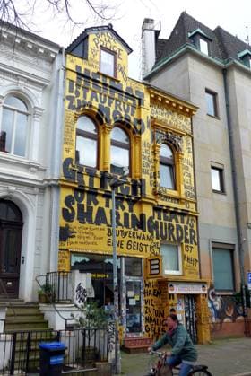 In einer Seitenstraße des Bremer Steintorviertels steht ein Wohn- und Geschäftshaus mit komplett bemalter Fassade. Unten residiert der Buch- und Schallplattenladen Golden Shop.