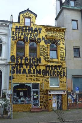 In einer Seitenstraße des Bremer Steintorviertels steht ein Wohn- und Geschäftshaus mit komplett bemalter Fassade. Unten residiert der Buch- und Schallplattenladen Golden Shop.