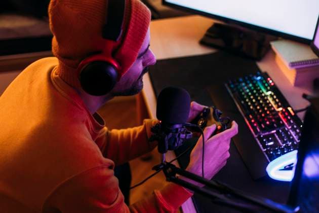 IMAGO Creative, Lifestyle, Gaming Gaming influencer wearing wireless headphones and playing video games at home model released, Symbolfoto property released, EGHF00836