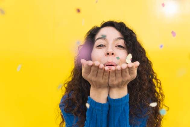 Creative Highlights Symbolbilder Woman blowing colorful confetti against yellow background model released, Symbolfoto, MGRF01094