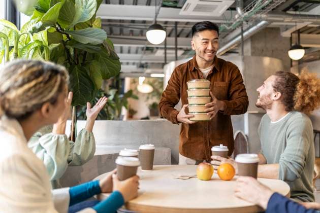 Smiling businessman holding stack of containers at lunch break in office model released, Symbolfoto property released, JCCMF11304