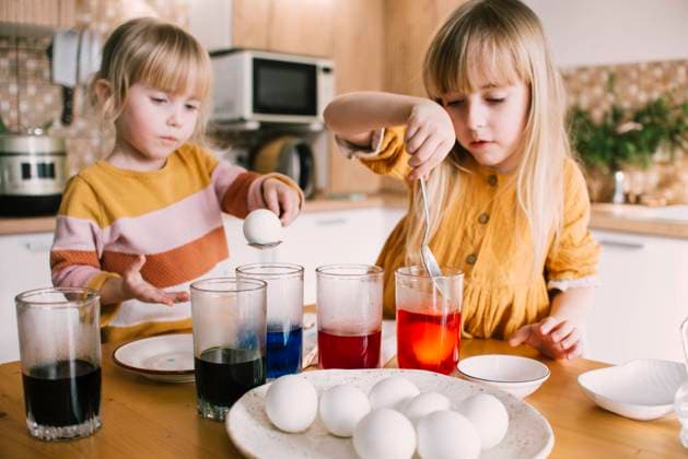 Sisters dipping Easter eggs in colored dye at home model released, Symbolfoto property released, ASHF00052