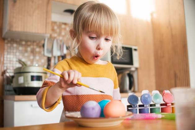 Creative Highlights Symbolbilder Surprised girl coloring Easter eggs with paintbrush at home model released, Symbolfoto property released, ASHF00059