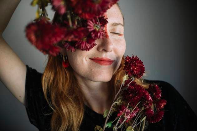 Creative Highlights Symbolbilder Smiling woman with eyes closed holding flowers against gray background model released, Symbolfoto property released, ASHF00074
