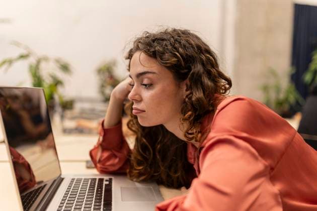 Bored businesswoman looking at laptop on desk at office model released, Symbolfoto property released, JCCMF11393