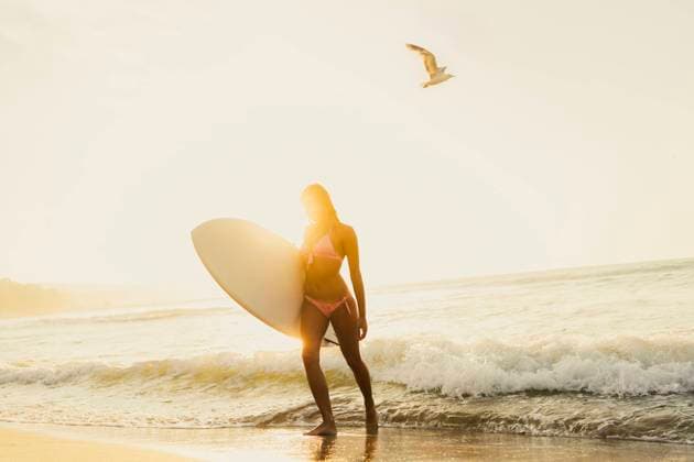 Young woman walking with surfboard near waves at sunset model released, Symbolfoto, AAZF01662