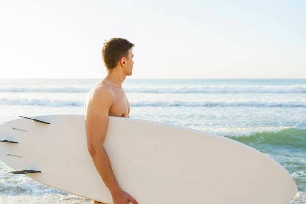 Young man carrying surfboard and looking at sea model released, Symbolfoto, AAZF01671