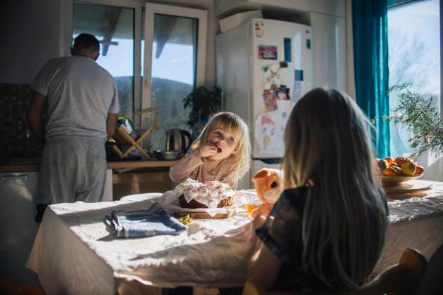 Girl eating cake in kitchen near family at home model released, Symbolfoto property released, ASHF00085