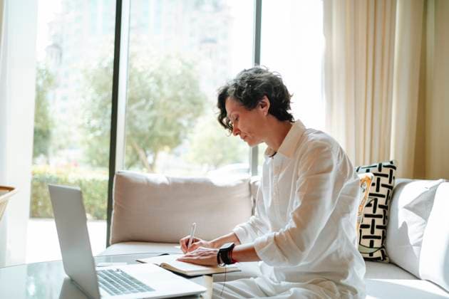 Confident businesswoman writing in diary by laptop at hotel lobby model released, Symbolfoto property released, MDOF01880