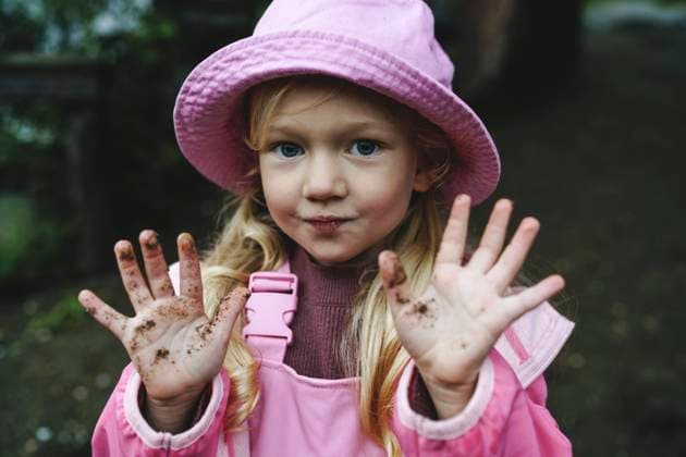 Creative Highlights Symbolbilder Girl in pink raincoat and hat showing dirty hands model released, Symbolfoto, NSTF00026