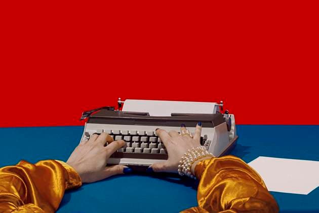 Writer typing on typewriter at desk against red background model released, Symbolfoto, RDTF00015