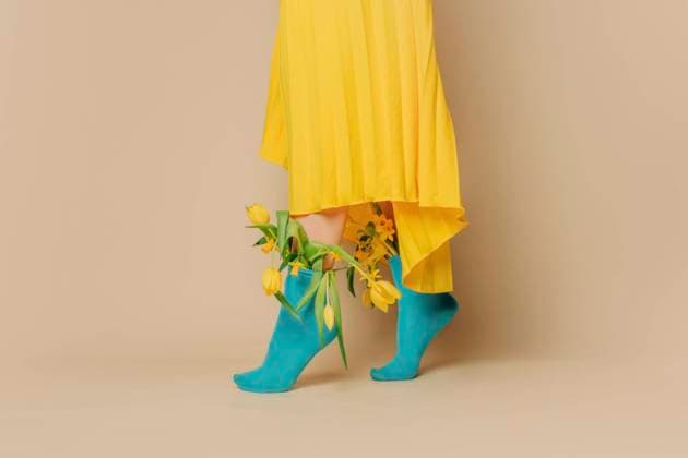 Creative Highlights Symbolbilder Woman wearing yellow skirt with tulips in blue socks against beige background model released, Symbolfoto, VSNF01694