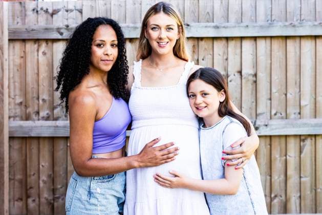 Creative Highlights Symbolbilder Smiling pregnant woman standing with family near fence model released, Symbolfoto property released, WPEF08413