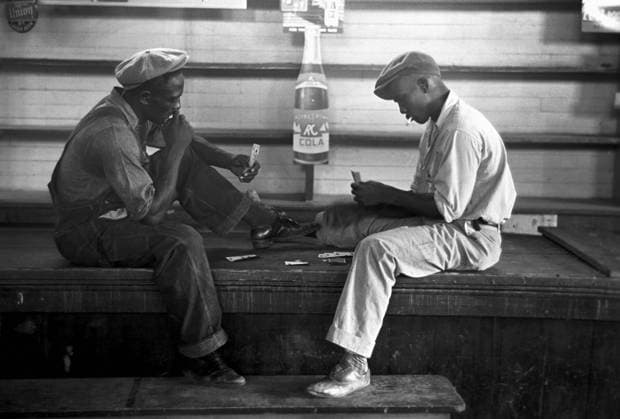 CARD GAME, 1938. Two African American workers playing the card game coon-can or conquian, in the back storeroom near Reserve, Louisiana. Photograph by Russell Lee, September 1938.  Copyright: xGRANGERx xGRANGERx 0121657