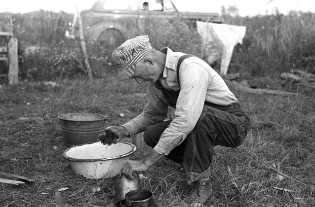 SHANTYTOWN, 1938. Migrant worker using a washbin to clean the dishes near his shack in a shantytown near New Iberia, Louisiana. Photograph by Russell Lee, November 1938.  Copyright: xGRANGERx xGRANGERx 0121700