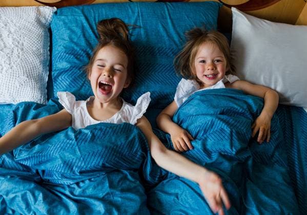 Creative Highlights Symbolbilder Two small smiling cute sisters are lying in bed, top view. Gera, Thuringia, Germany CR_GGIE2403224F-1376432-01 ,model released, Symbolfoto