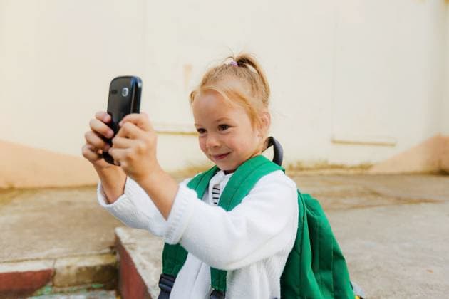 A little girl with a backpack takes a photo on her smartphone Gera, Thuringia, Germany CR_GGIE240322C-1376384-01 ,model released, Symbolfoto
