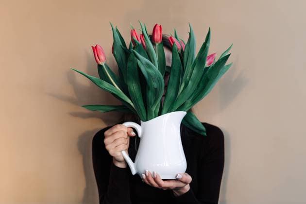 Woman covering face with bouquet of tulips in white porcelain jug Vilnius, Vilnius County, Lithuania R_EDSAHG240321-1372166-01 ,model released, Symbolfoto