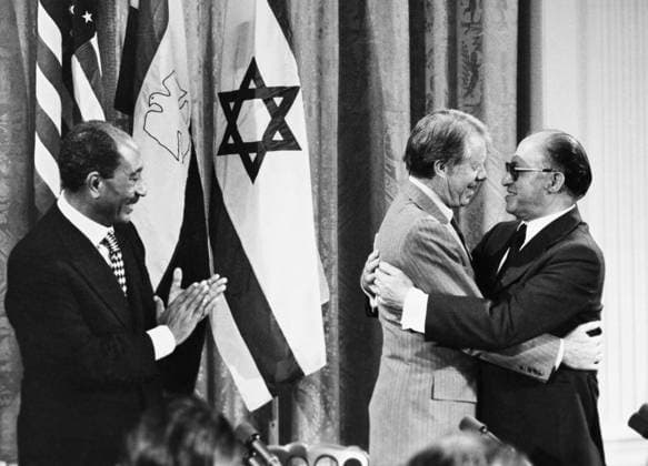 CAMP DAVID SUMMIT, 1978. President Anwar Sadat of Egypt applauds as U.S. President Jimmy Carter embraces Prime Minister Menachem Begin of Israel during a press conference September 1978.  Copyright: xGRANGERx xGRANGERx 0129620