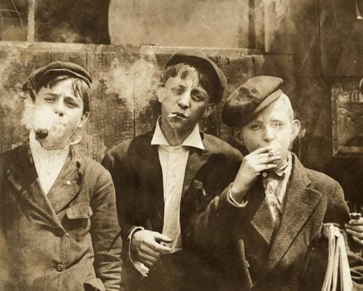 NEWSBOYS SMOKING, 1910. Three young newboys smoking cigarettes in St. Louis, Missouri. Photograph by Lewis Hine, May 1910.  Copyright: xGRANGERx xGRANGERx 0131813