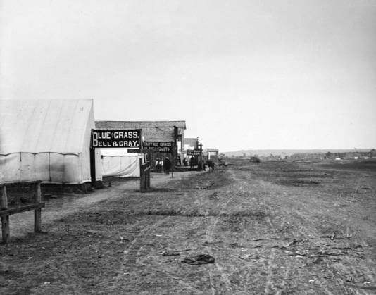 MONTANA: MILES CITY, c1880. View of a street in Miles City, Montana, showing signs promoting the sale of blue grass and buffalo grass, and a saloon farther down the road. Photographed by L.A. Huffman, c1880.  Copyright: xGRANGERx xGRANGERx 0184287