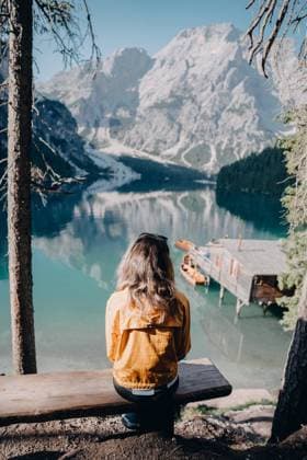 Creative Highlights Symbolbilder Female tourist in Italy looking at lake while sitting on bench Urtijëi, Trentino-South Tyrol, Italy CR_BUEM240325-1358029-01 ,model released, Symbolfoto