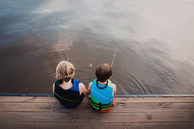 Creative Highlights Symbolbilder Two children in life jackets sit by the lake, fishing lines in water Eatonton, Georgia, United States CR_RCYA240326-1376596-01 ,model released, Symbolfoto