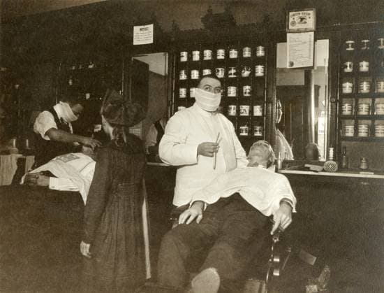 FLU PANDEMIC, 1918. A barber in Cincinnati, Ohio, wearing a face mask during the influenza pandemic. Photograph, October 1918.  Copyright: xGRANGERx xGRANGERx 0529222