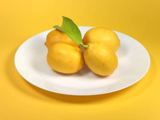 lemons in a dish four lemons in a dish over yellow background with copy space Copyright: xZoonar.com ClaudioxDiviziax 20172124