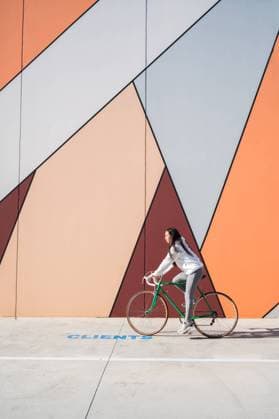 Creative Highlights Symbolbilder Sportswoman riding green bicycle on street near wall with art Vilafranca del Penedès, Catalonia, Spain CR_SCLO240327-1373193-01 ,model released, Symbolfoto