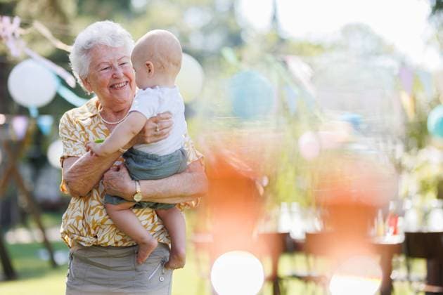 Great-grandmother holding little baby in her arms. Family summer garden party. Portrait of great-grandmother holding a tiny baby in her arms. Family summer garden party. model released