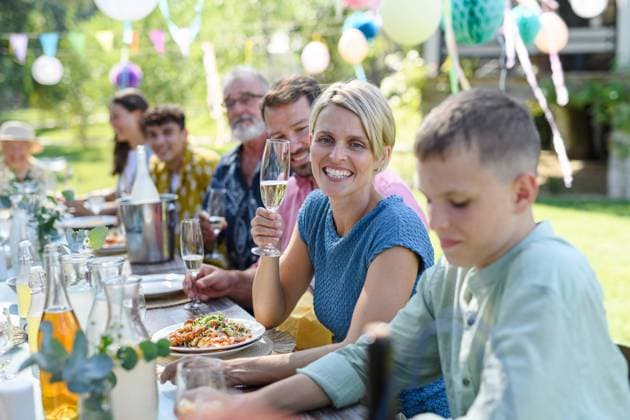 Family chatting, and having fun at party table during summer garden party. Beautiful woman cheering with glass with champagne. Family chatting, and having fun at party table during summer garden party. Beautiful woman toasting, cheering with glass with champagne. model released