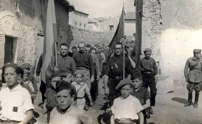 Snapshot of the procession on the day of the Caudillo along the streets of Alba in 1938, during the Spanish civil war. Children, men wearing the typical fascist black shirts and soldiers are walking along yhe street carrying the Spanish and Italian flags (b w photo) 1250089 Snapshot of the procession on the day of the Caudillo along the streets of Alba in 1938, during the Spanish civil war. Children, men wearing the typical fascist black shirts and soldiers are walking along yhe street carrying the Spanish and Italian flags (b w photo) by Unknown photographer, (20th century); (add.info.: Unidentified Author Spain); Fratelli Alinari Museum Collections, Florence, Italy. Copyright: xFratellixAlinarixMuseumxCollections,xFlorence,xItalyx xBridgemanxImagesx 1250089