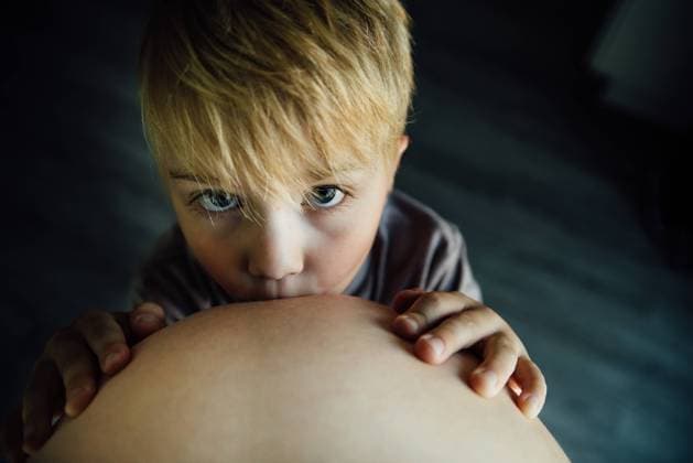 Creative Highlights Symbolbilder Portrait of small boy kissing moms pregnant baby belly indoors United States, North Dakota, Bismarck CR_KIFR240402-1377376-01 ,model released, Symbolfoto