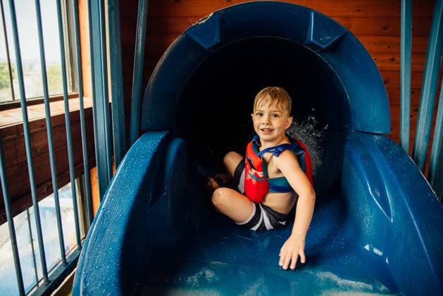 Creative Highlights Symbolbilder Little boy looking back and camera at top of waterslide indoors United States, South Dakota, Custer CR_KIFR240402-1377396-01 ,model released, Symbolfoto