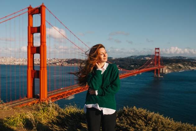 Creative Highlights Symbolbilder A young woman enjoys the warmth of the spring sun with the iconic Golden Gate Bridge and San Francisco skyline in the distance Model Released CamilleGirard_ID20234_598643_027 Copyright: xCamillexGirardx