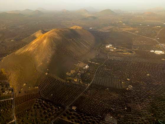 Drone captures the warm sunset light bathing the volcanic cones and cultivated fields of Lanzarote, creating a stunning, textured landscape Model Released JuanAizpuru_ID20115_595459_002 Copyright: xJuanxAizpurux